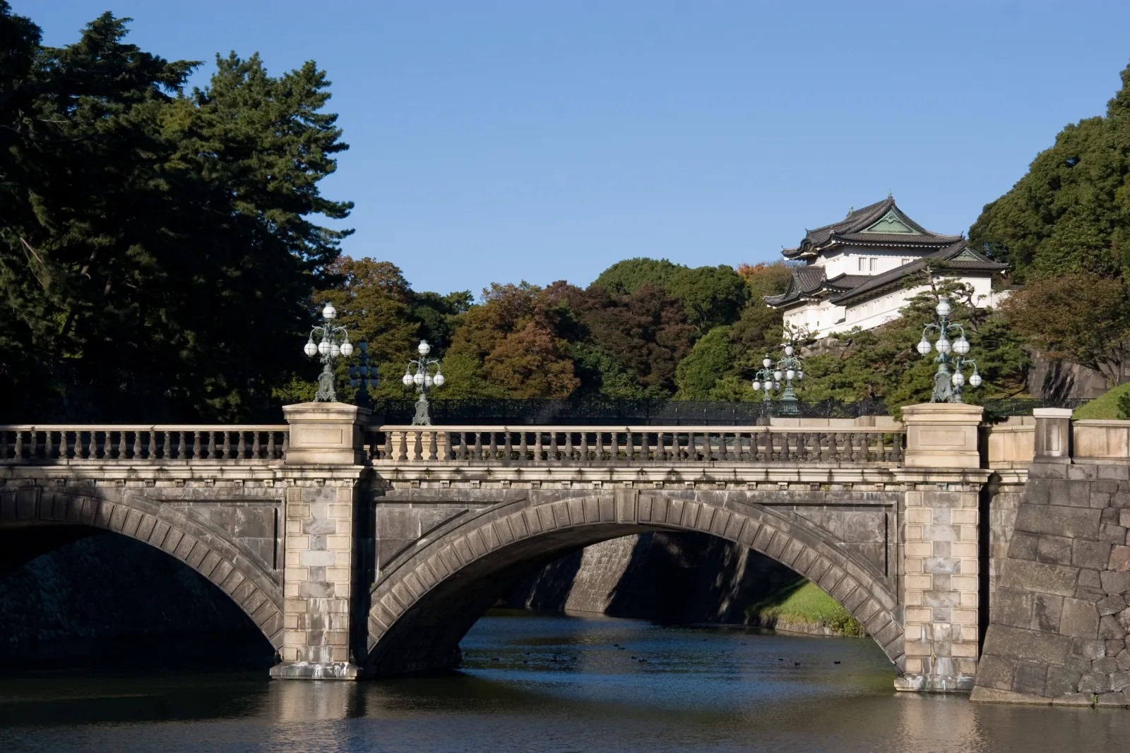 The stone bridge across the palace moat, a white turret behind