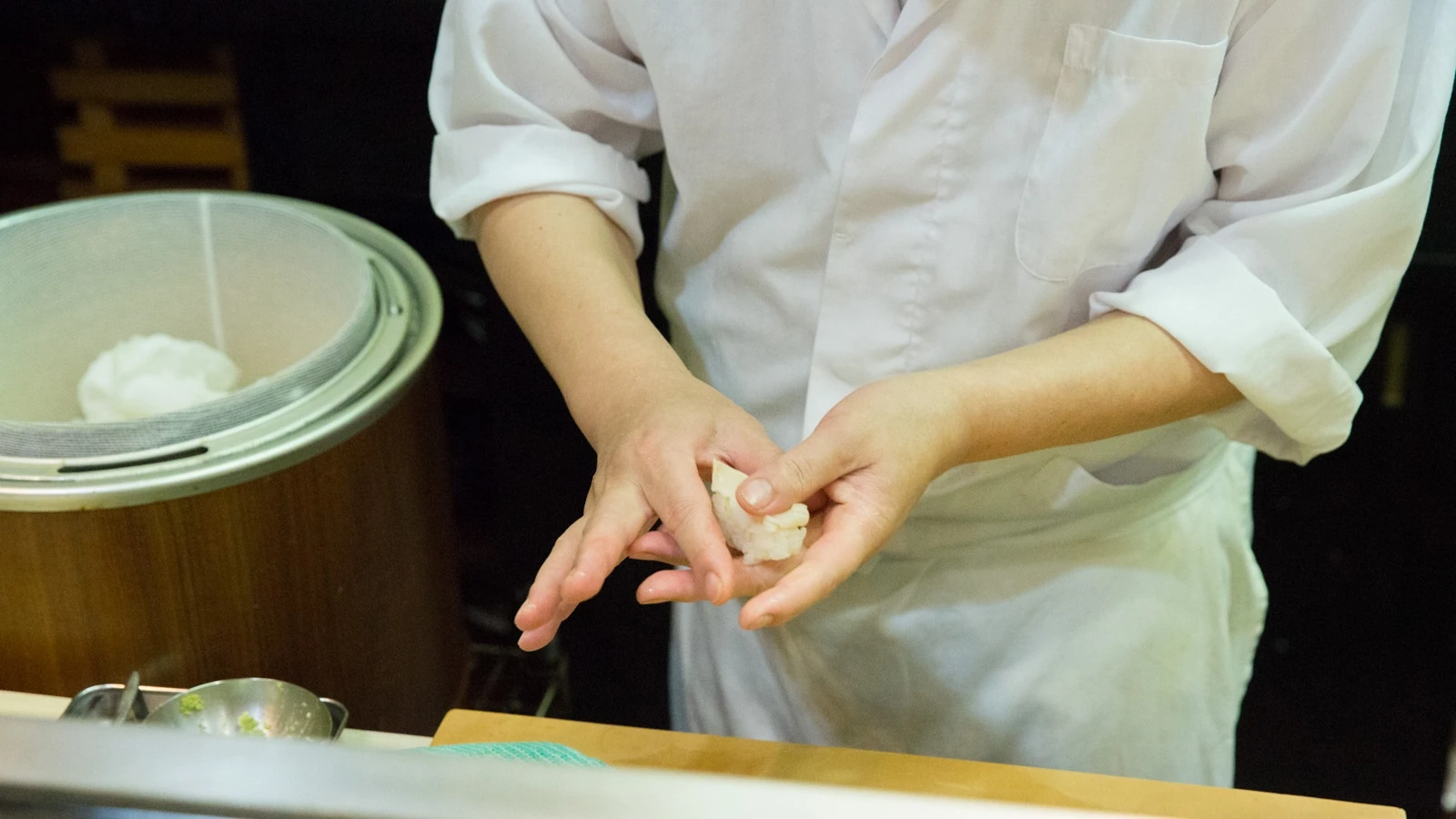 A chef shaping nigiri at the counter