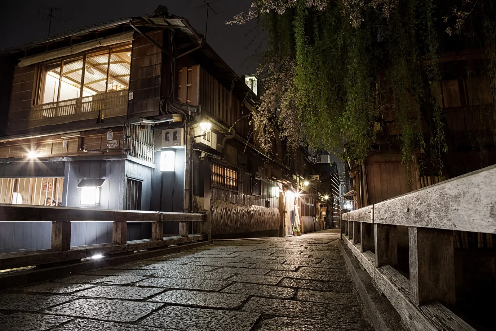 A stone-paved Gion lane as the lamps come on