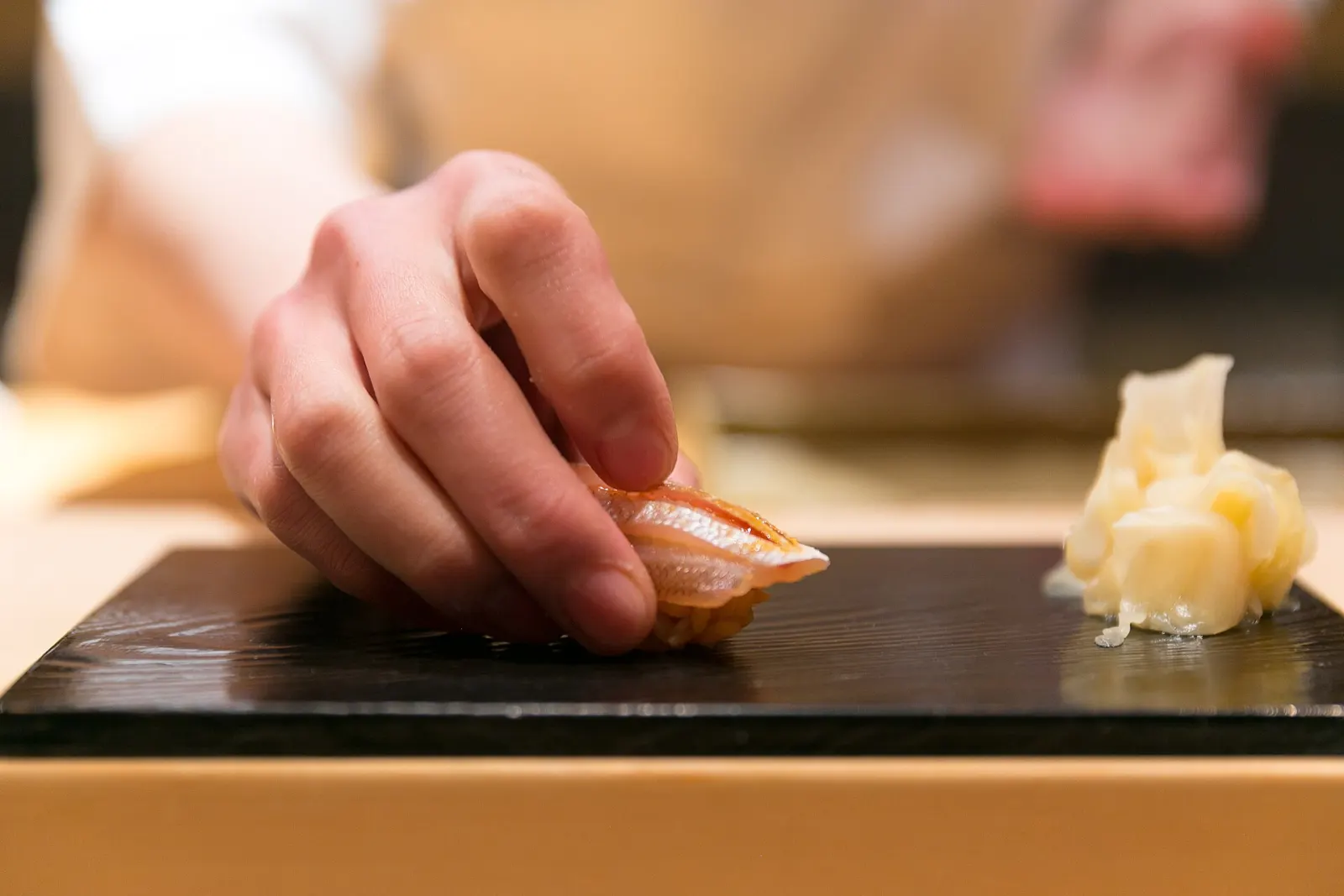 A chef setting down a piece of sea bream nigiri
