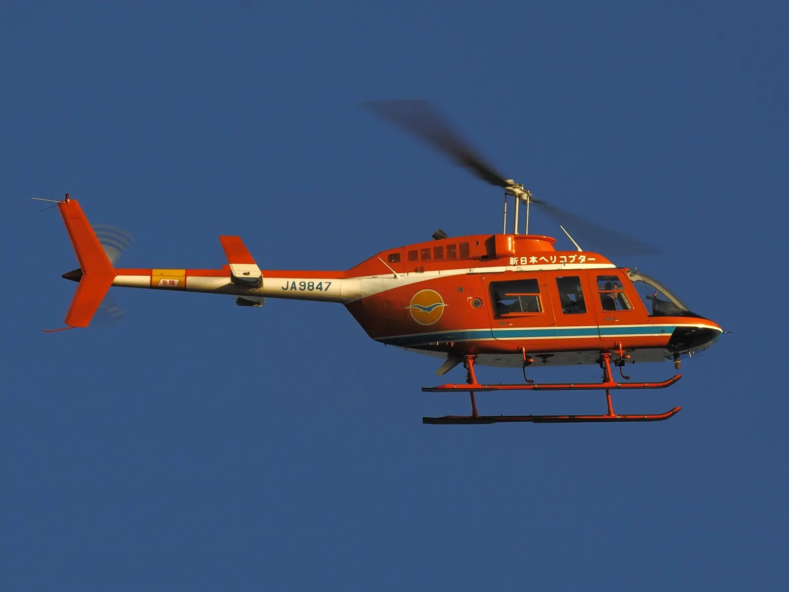 An orange helicopter against a deep blue sky