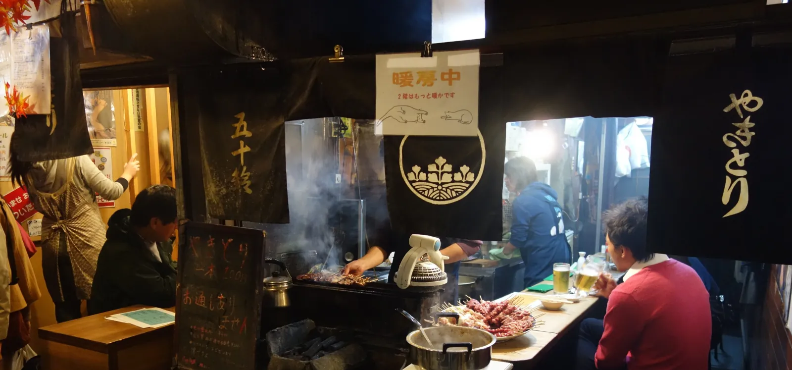 Diners at a smoky counter, the cook at the grill