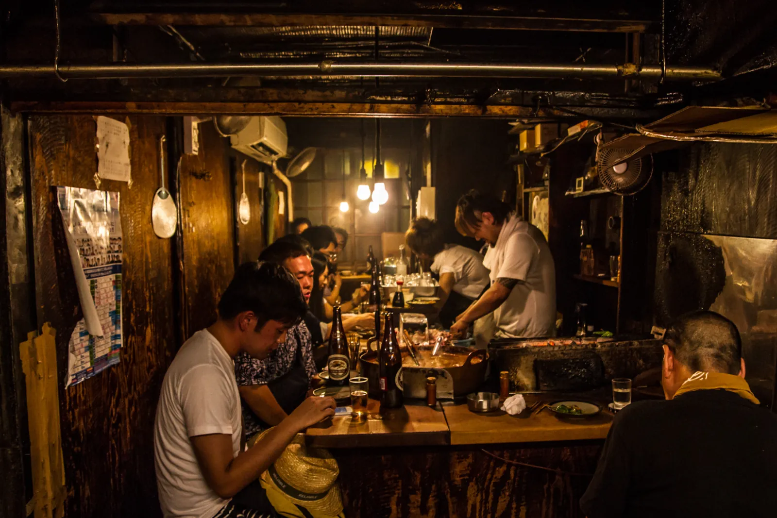 A small, smoky izakaya, the cook at work among the diners
