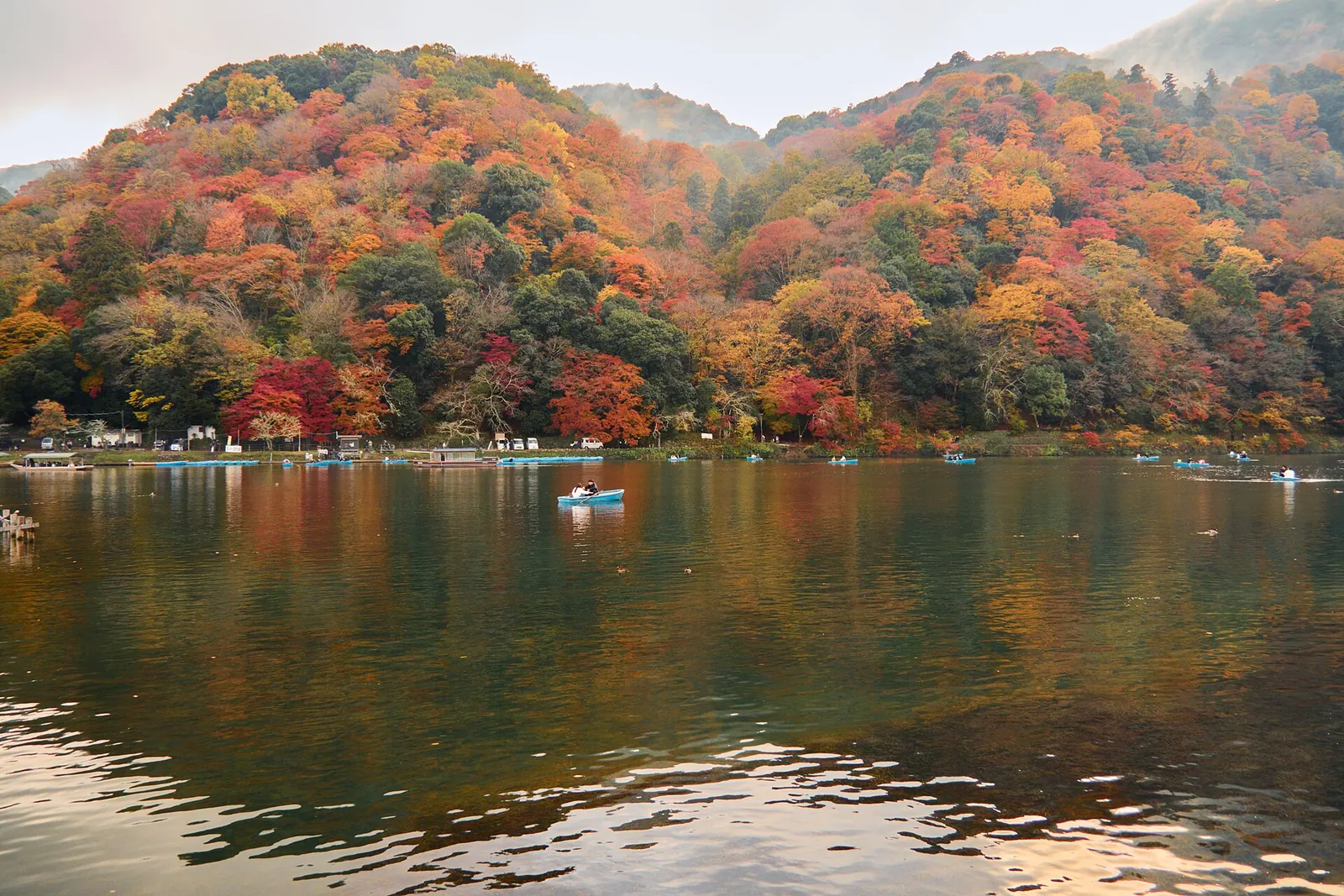 Boats on the river under Arashiyama's autumn hills