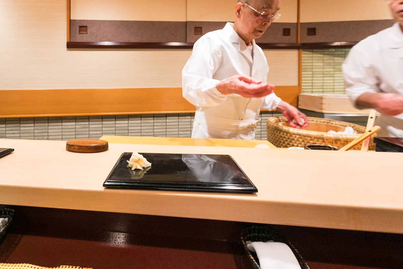 A sushi master shaping nigiri across the counter